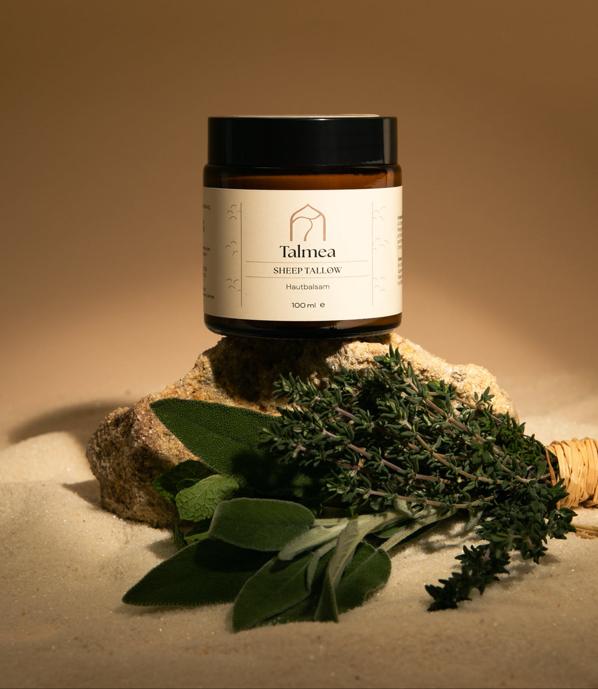 Talmea Sheep Tallow 100 ml auf Naturstein mit gebündelten Kräutern im warmen Licht