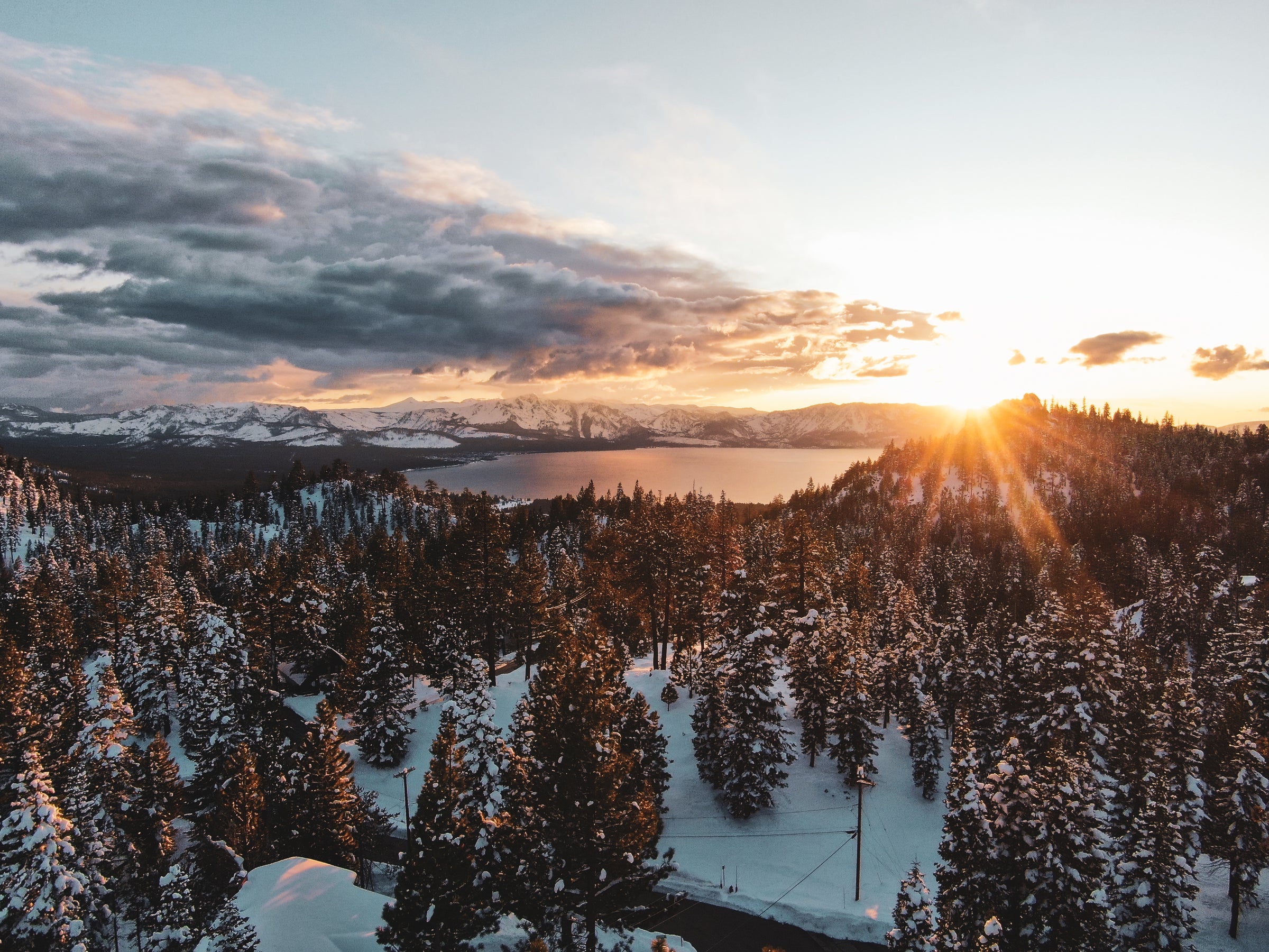 Winterlandschaft mit Tannenwald und See bei Sonnenaufgang aus der Vogelperspektive